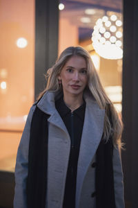 Portrait of young woman standing against wall