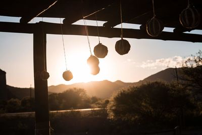 Low angle view of lighting equipment hanging against sky during sunset