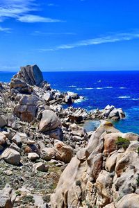 Aerial view of rocks and sea against blue sky