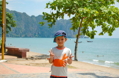 Portrait of boy gesturing peace sign at promenade