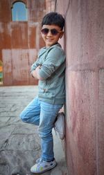 Portrait of boy wearing sunglasses standing by wall