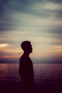 Silhouette man looking at sea against sky during sunset