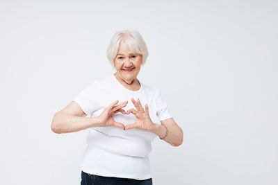 Portrait of young woman with arms crossed standing against white background