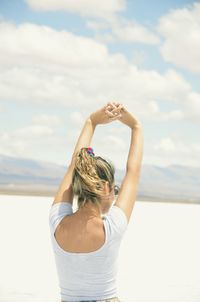 Rear view of woman with arms raised standing by lake