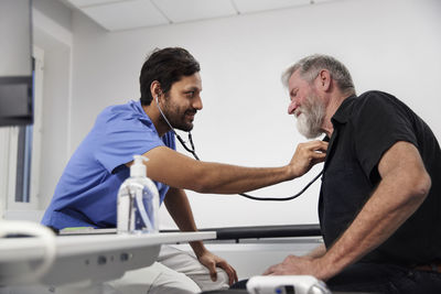 Male doctor examining senior patient with stethoscope