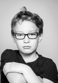 Portrait of boy wearing eyeglasses against gray background