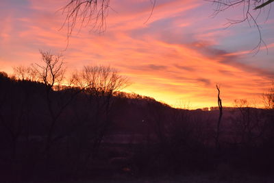 Silhouette bare trees on landscape against romantic sky at sunset