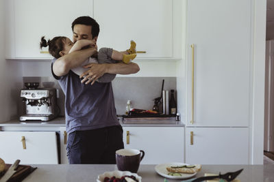 Father playing with son in kitchen at home