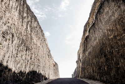 Empty road between rock formations against sky