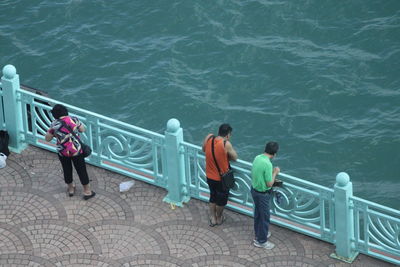 High angle view of people standing by railing and sea