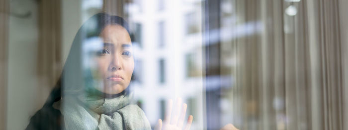 Thoughtful young woman looking through window