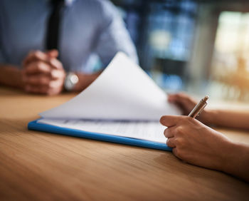 Midsection of man writing in book