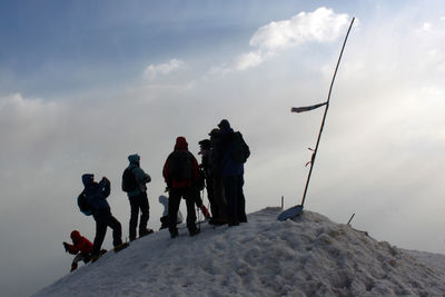 People on snow covered mountain against sky