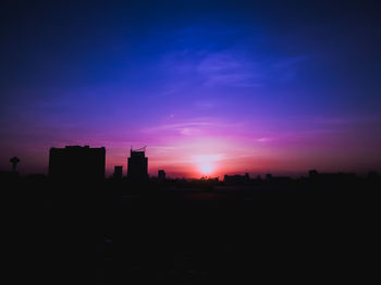 Silhouette buildings against sky at sunset