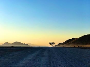 Scenic view of road against clear sky during sunset