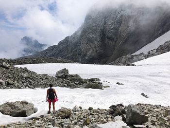 Rear view of woman standing on rock against mountains