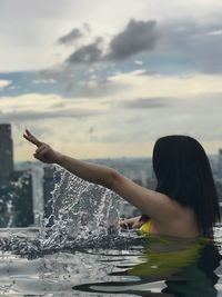 Woman swimming in infinity pool against sky