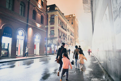 Rear view of people walking on street in rain