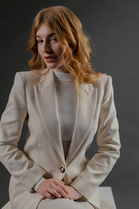 Portrait of young woman standing against black background