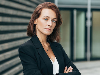 Portrait of young woman standing against wall