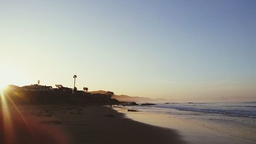 Scenic view of beach against clear sky during sunset