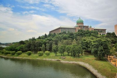 Building by river against cloudy sky