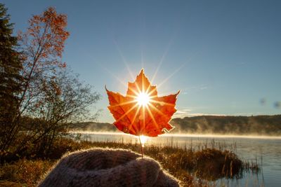 View of sun shining over lake during sunset