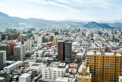 High angle view of urban skyline against cloudy sky