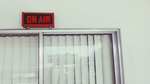 Low angle view of on air sign over window on wall