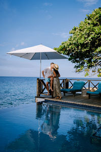 Couple kissing under umbrella by sea