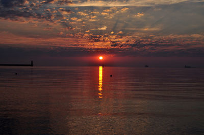 Scenic view of sea against cloudy sky during sunset