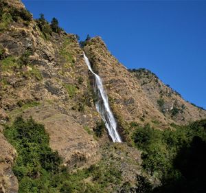 Scenic view of waterfall against clear blue sky
