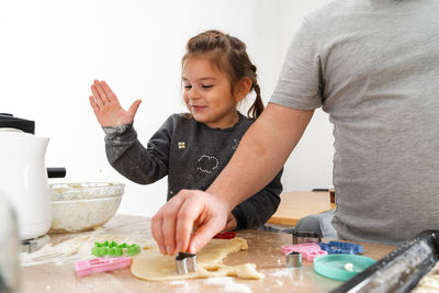 Midsection of father making cookie with daughter