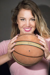 Portrait of a smiling young woman holding ball