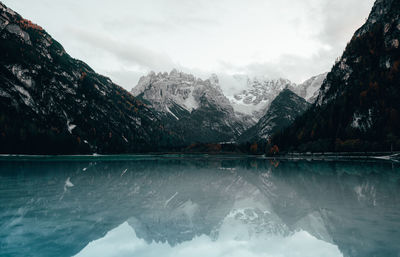 Scenic view of lake by snowcapped mountains against sky