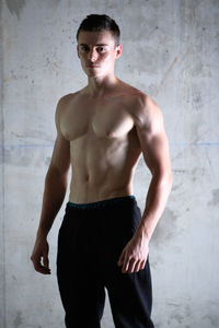 Young muscular man standing against wall