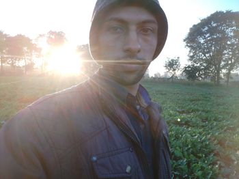Portrait of young man on field against trees