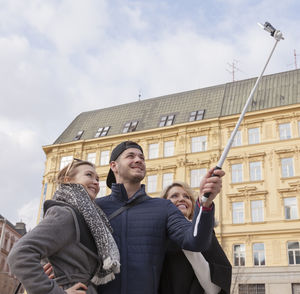 Low angle view of friends in city against sky