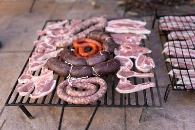 Grill full with different types of raw meat ready for getting cooked in the barbecue.