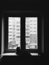 Woman looking through window at home