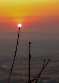 Silhouette wooden post in sea against sky during sunset