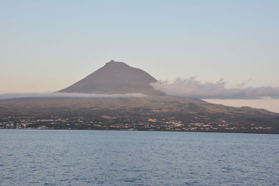 Scenic view of sea by mountains against clear sky