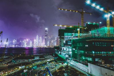 Illuminated modern buildings in city against sky at night