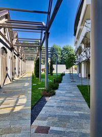 Footpath amidst buildings against clear blue sky