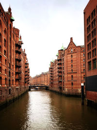 Canal amidst buildings in city against sky