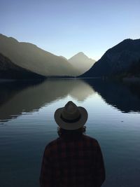 Rear view of man looking at lake against sky