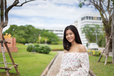 Portrait of smiling young woman standing at park