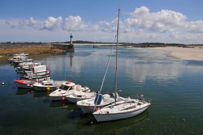 Sailboats moored on sea against sky