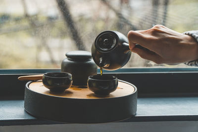 Close-up of hand holding tea cup on table