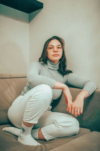 Portrait of young woman sitting on sofa at home